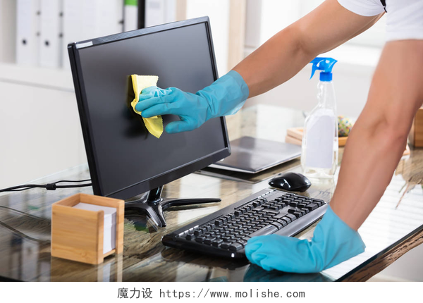 一个人戴着手套拿着抹布擦拭计算机屏幕看门人清洁电脑屏幕